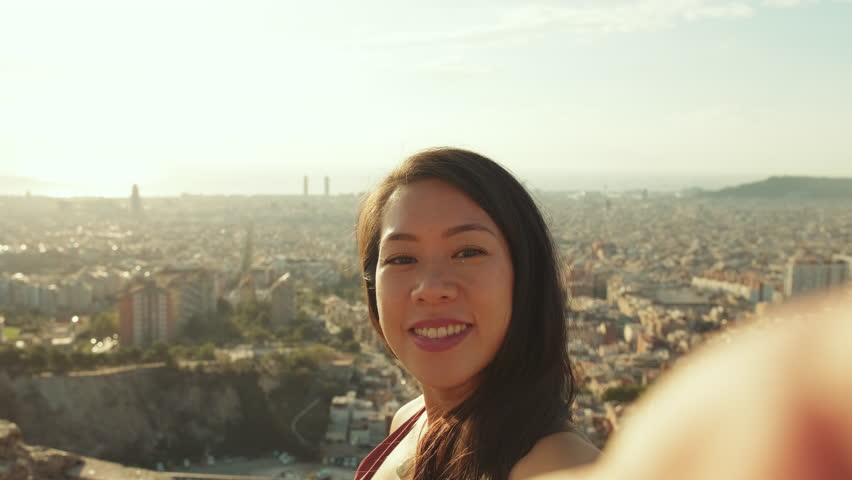 Close up, laughing sporty woman making video call from mobile phone while standing at lookout point