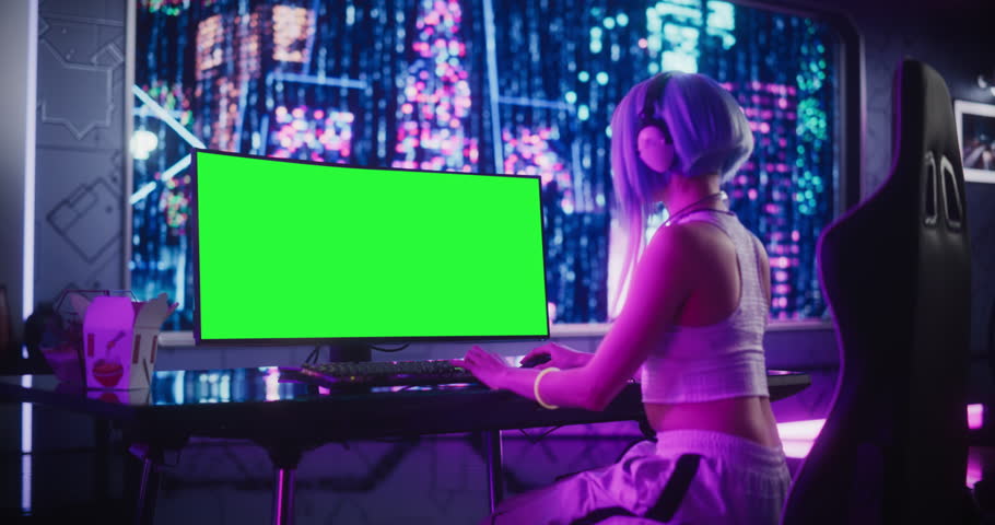 Young Woman Playing Online Video Game on a Computer with Green Screen Mock Up Display in a Futuristic Digital Space. Stylish Cyberpunk Cosplay Content Creator with Blue Hair. Footage from the Back Royalty-Free Stock Footage #1102884979