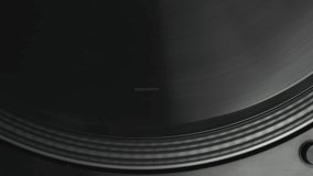 Black vinyl record spinning on a turntable player. Overhead 4K video clip of a DJ deck playing music