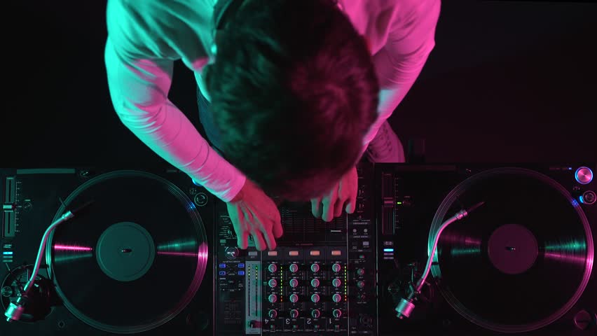 Club DJ mixing vinyl records on stage. Disc jockey playing music on a party, filmed from above Royalty-Free Stock Footage #1102888441