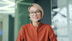 Webcam view. A corporate operator who works in the support service speaks on a video call while looking into the camera. A call center agent in a wireless headset helps a customer with a complaint - Powered by Shutterstock - Get 15% off with code: PIKWIZARD15