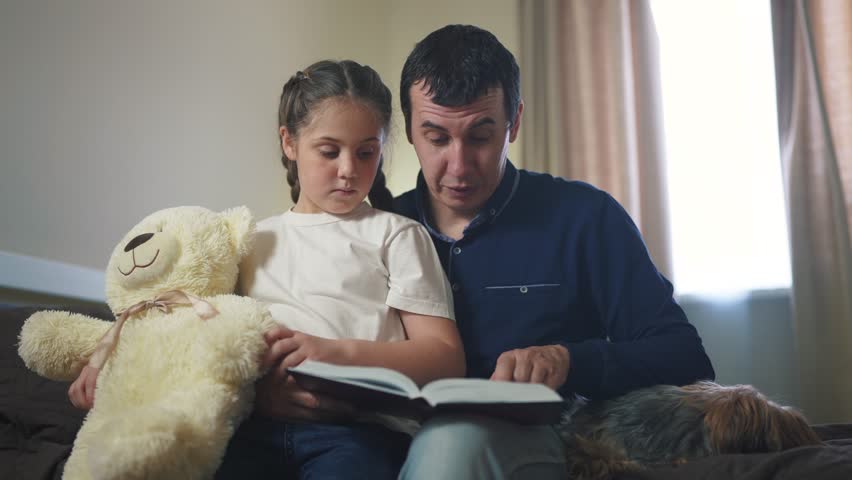 dad reading book to daughter in bedroom. happy family kid dream concept. father parent reads a book at night to his daughter child. dad lifestyle and daughter care and guardianship Royalty-Free Stock Footage #1102890441