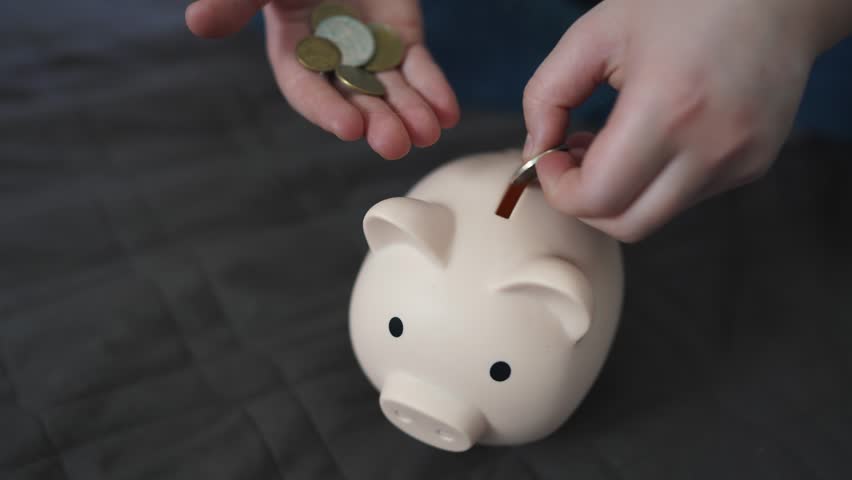 child hands hoarding coins put in piggy bank. happy family accumulation business concept. child saving coins in a piggy bank close-up. child hands puts coins in a large piggy bank indoors dream Royalty-Free Stock Footage #1102890477