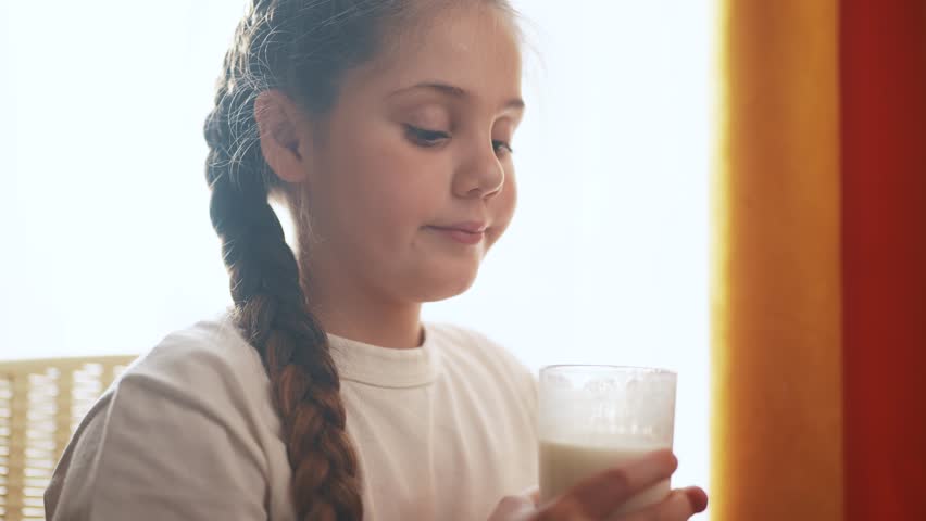 child girl drinks milk from glass in the kitchen. happy family healthy eating concept. baby girl and glass of milk close-up. child girl enjoying warm milk in the kitchen lifestyle Royalty-Free Stock Footage #1102890487