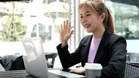Asian businesswoman video call with laptop in coffee shop, work from anywhere, wireless technology 5G.