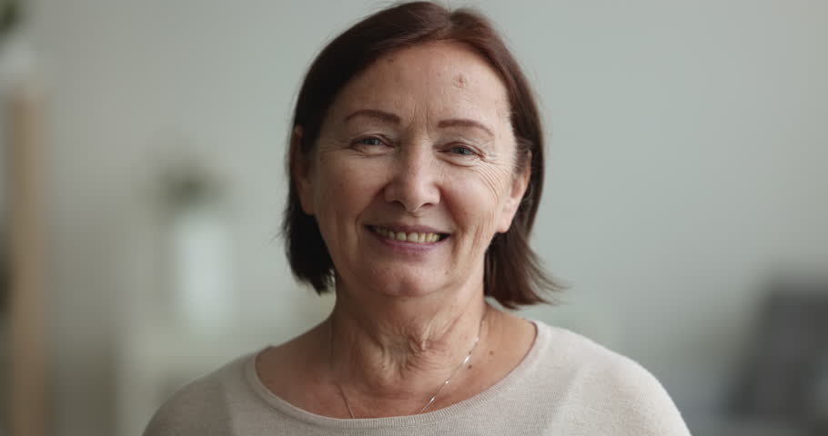 Close up happy brown-haired mature woman smiling look at camera. Head shot portrait optimistic cheerful elderly female enjoy carefree life on retirement, feel satisfied and confident, profile picture