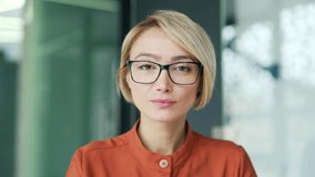 Close up portrait of a young confident female employee in a modern office. Serious stylish blonde businesswoman in glasses is looking at the camera. A successful manager, lawyer or woman entrepreneur - Powered by Shutterstock - Get 15% off with code: PIKWIZARD15