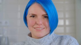 Portrait of cheerful Ukrainian woman with dyed blue hair. Cute millennilal female posing for a video 