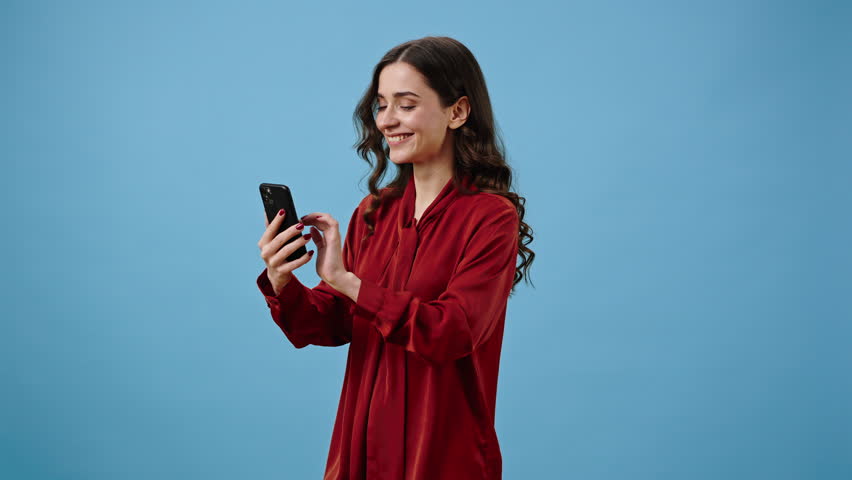Successful woman works on phone app and recommends useful program showing thumb-up. Lady calls for participation pointing finger at device against blue wall Royalty-Free Stock Footage #1102906255
