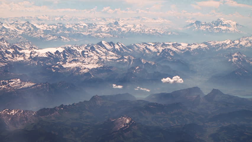 High angle aerial above Mountains with snowy peaks during sunny and cloudy day - Panoramic shot