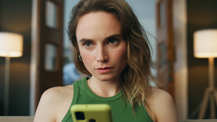 Focused lady messaging smartphone at home zoom on. Serious woman creating email texting mobile phone at living room closeup. Involved girl typing cellphone screen sitting couch. Communication concept