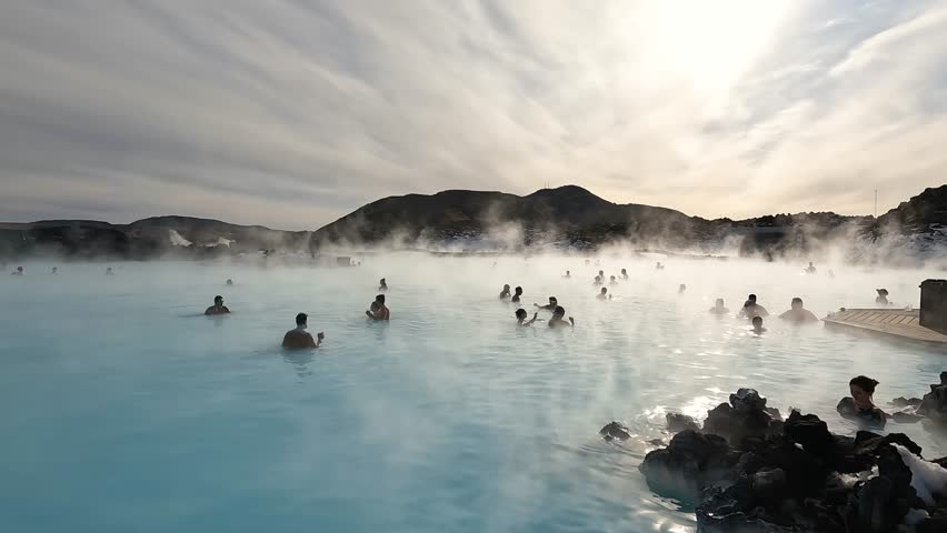 SPA in Iceland. Blue Lagoon, Iceland. Misty hot spring with tourists during sunny day. Geothermal spa in lava field. Royalty-Free Stock Footage #1102919893