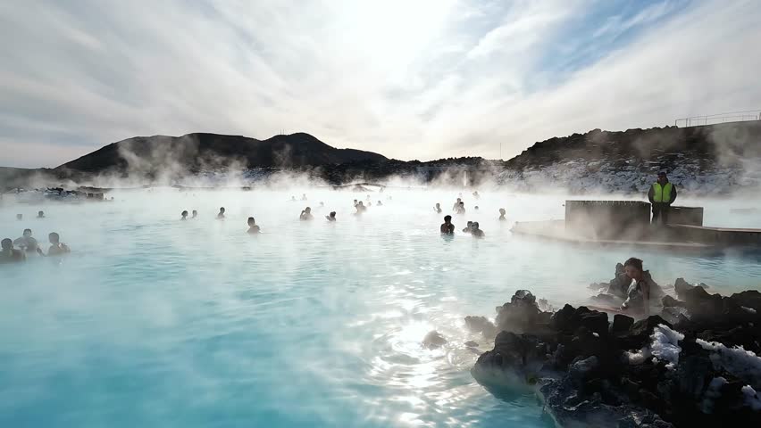 SPA in Iceland. Blue Lagoon, Iceland. Misty hot spring with tourists during sunny day. Geothermal spa in lava field. | Shutterstock HD Video #1102919895