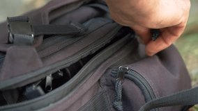 Close up man hand closes the backpack with the zip. Slow motion 4K