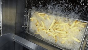 a wire basket of french fries in an oil bath, frying, vertical video