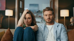 Sad family sitting sofa at living room zoom out. Serious boyfriend girlfriend involved in interesting tv show chilling couch together pov view. Unhappy couple watching television after quarrel closeup - Powered by Shutterstock - Get 15% off with code: PIKWIZARD15
