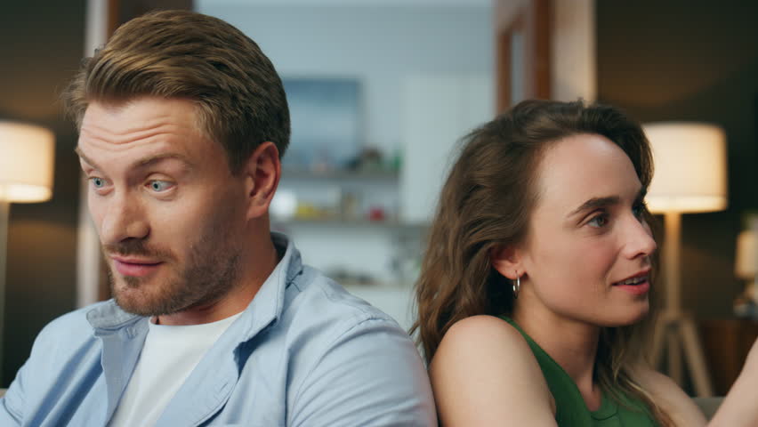 Closeup relaxed couple talking at home weekend. Handsome happy man speaking to wife showing tablet indoors. Young woman reacting at husband joke laughing at sofa. Lazy love pair resting with gadgets Royalty-Free Stock Footage #1102926869