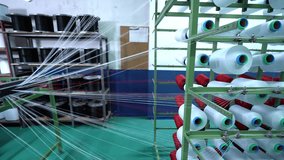 Spinning spools in the textile factory unit. close-up spools of yarn thread industrial warping machine in textile factory plant machine spools clews fiber on rack Textiles equipment in work.4K video.