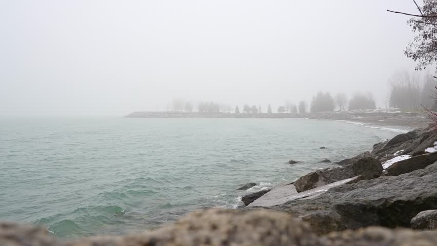Foggy Lake Ontario scene in Canada slow motion. Winter season with mystic dark foggy landscape. Scary mystical heavy fog smoke and mist mood.
