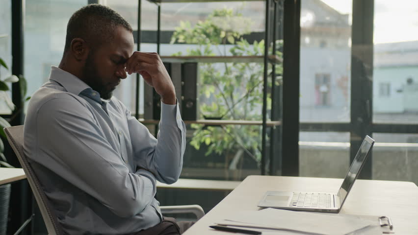 Overworked African American mature man working laptop in office suffer with eye strain exhausted sick fatigued male senior businessman feel pain discomfort eyesight headache migraine health problem Royalty-Free Stock Footage #1102934969
