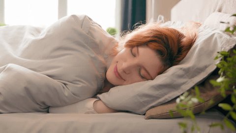 Caucasian happy woman sleeping in comfortable cozy bed at home girl lady asleep lying on soft pillow white linen orthopedic mattress resting relaxing napping healthy sleep nap in morning stress relief Video de stock