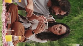 VERTICAL VIDEO: Couple in love enjoying snacks and using mobile phone