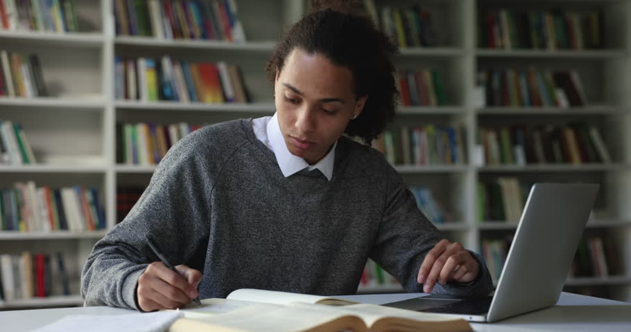 Serious Latin student guy absorbed in studies, makes assignment, prepare for university admission looks focused sit at desk e-learning using laptop, get new knowledge, improve English skill. Education Royalty-Free Stock Footage #1102943893