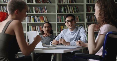 Diverse students take part in group teamwork seated at desk, Indian school-boy makes speech, share ideas with groupmates during education seminar, prepare together to exams in college library. Study – Video có sẵn