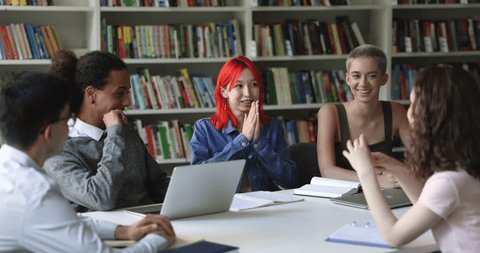 Teen student girl with dyed red hair make speech at group meeting in library with teammates, share ideas, prepare common assignment or project engaged in creative teamwork studying together. Education Video de stock