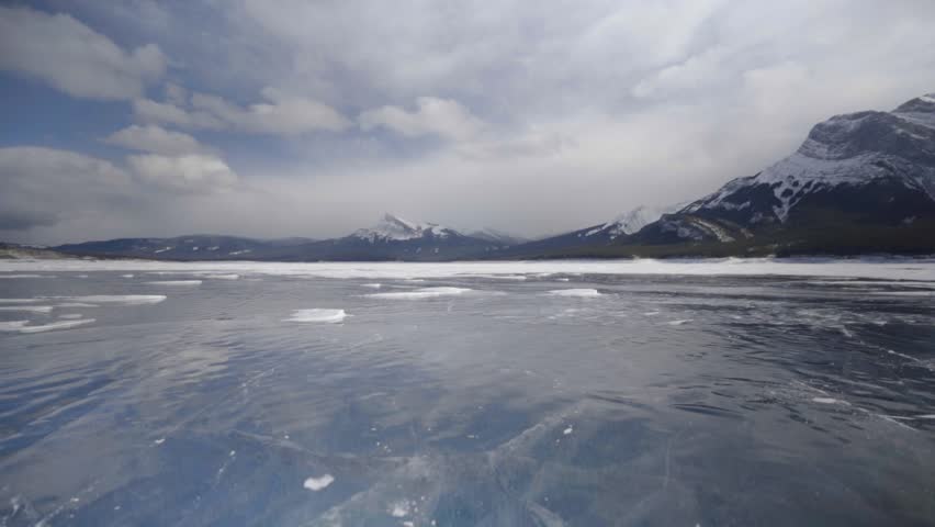 man ice skating on frozen abraham lake in alberta canadian rockies
