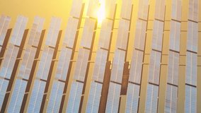 A beautiful scene from above as the sun sets, the solar power plant sprawls out with rows of shining solar panels capturing the last rays of light. Clean and renewable energy concepts. 4K Drone
