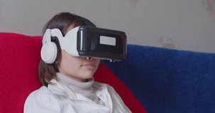 Teenage girl in virtual reality glasses. She flips through virtual books Online learning at home.