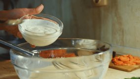 Mixing fresh eggs with steel hand mixer in a glass bowl. Adding flour. Process of preparing pancakes. 4K video