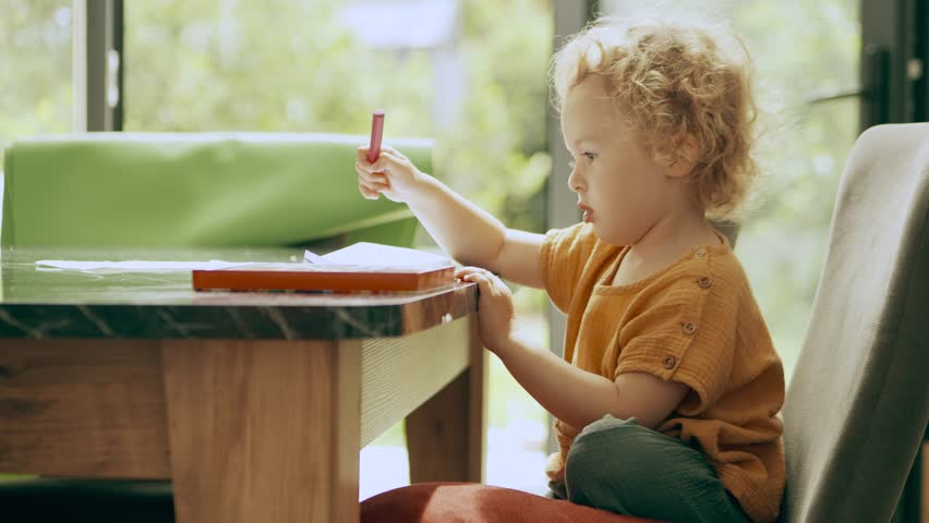 Smart little girl thinks over a new picture at home