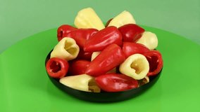 Plate red sweet peppers and sweet yellow peppers in row on white background. Loop motion. Side view. Rotation 360. 4K UHD video footage 3840X2160.