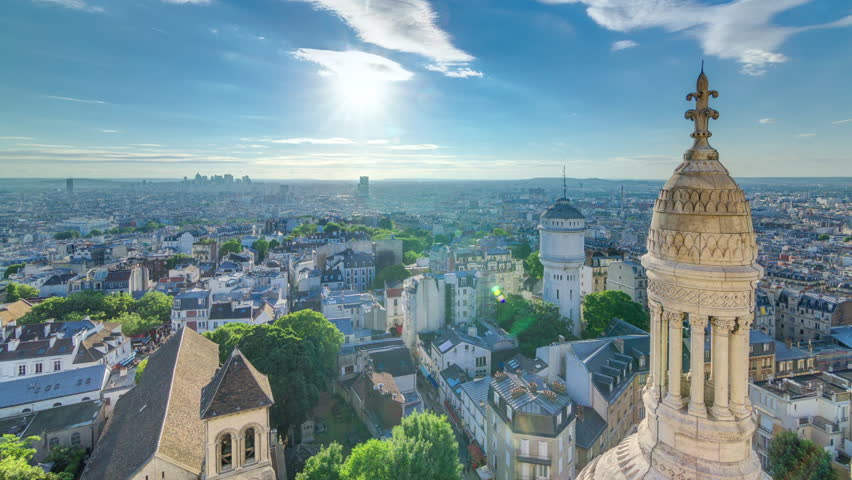 Panorama of Paris timelapse with sun before sunset, France. Business district skyscrapers on a background. Aerial top view from Montmartre viewpoint. Sunny day with blue cloudy sky.