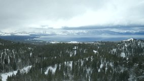 Magnificent lake in the middle of winter wonderland as seen from above. Cinematic natural background of Tahoe surroundings with dense, evergreen forest. High quality 4k footage