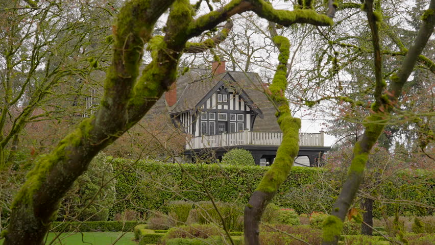 Establishing shot of two story stucco luxury house with garage door, big tree and nice spring blossom landscape in Vancouver, Canada, North America. Day time on Apr 2023. ProRes 422 HQ.