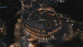Aerial drone view of the Colosseum at night, Rome, Italy, Europe. Ancient Roman ruin is the top landmark of Rome. Night view.