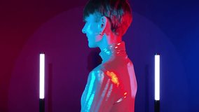 Female android robot changing synthetic smile to blank expression in neon illumination indoors. AI concept, sci-fi, future. Young adult woman in futuristic sparkling costume art colorful lighting - Powered by Shutterstock - Get 15% off with code: PIKWIZARD15