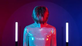 Female android robot turning on, having synthetic artificial smile in neon illumination indoors. AI concept, sci-fi, future. Young adult woman in futuristic sparkling costume art colorful lighting - Powered by Shutterstock - Get 15% off with code: PIKWIZARD15