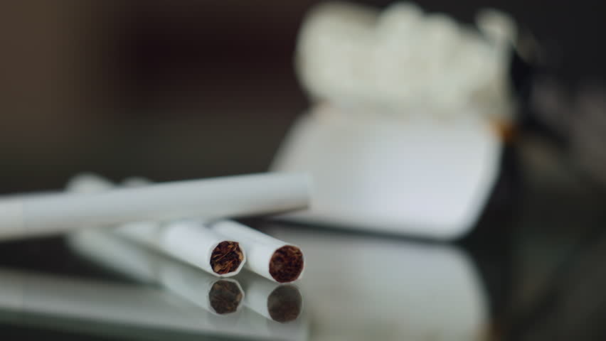 An open pack of cigarettes with cigarettes on the table. The focus shifts from the pack to the cigarettes. nicotine addiction. relieving stress and worries. a bad habit that leads to illness and death