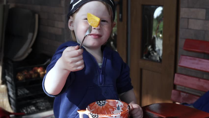 The child eats an orange and have fun.