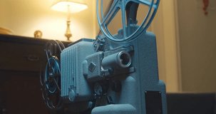 Vintage Movie Projector on Table With Cinematic, Dramatic Lighting. Vintage 8mm Film Projector With Spinning Reels and Old Film. Old Movie Projector is Showing a Movie, the Lamp.Projector Projecting 