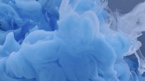 White and blue paint drops in water on a dark grey background, abstract and beautiful wave of ink. 8K downscale, a vertical frame slow motion. Filmed on cinema camera, 4K.