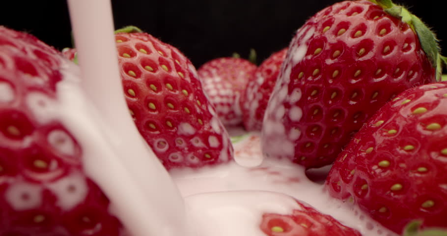 Extreme close-up, macro detailed of red strawberries of lie in yogurt. Sweet red berries covered with a white milky liquid. Pouring cream or yogurt over juicy fresh strawberries. 4K