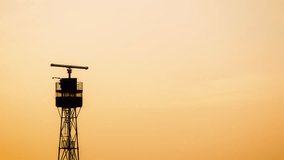 Time lapse of sea radar tower silhouette with spinning antenna at sunset. Sky for copy space 