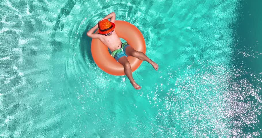 Boy swim in pool on inflatable ring from above. Kid with inflatable ring in swimming pool, top view. Summer vacation. Summer holiday weekend. Child in swiming pool. Kid floating in sea water. Royalty-Free Stock Footage #1103015907