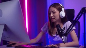 
Victory moment woman streamer wearing headphones playing game online and broadcast streaming studio in dark room neon light. Beautiful powerful female esports gamer play Cyber Gaming live at home.