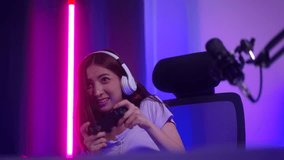 Happy fun moment Young woman streamer wearing headphones playing game online and broadcast streaming studio with neon light. Beautiful powerful female esports gamer play Cyber Gaming live at home.
